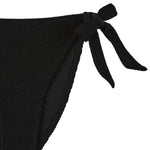 Flat lay side detail of the black Halo bikini bottoms showing the tie fastening