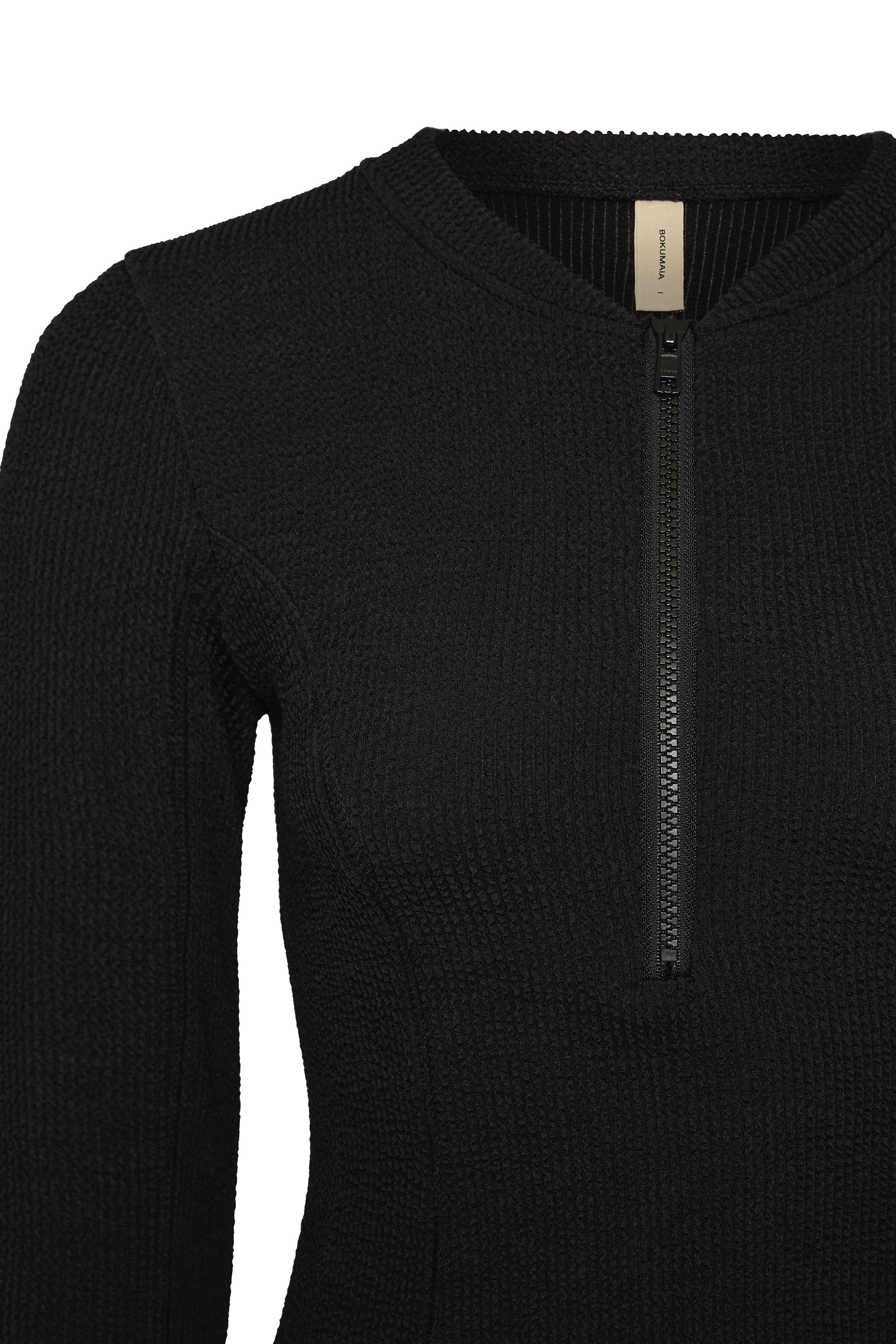 Flat lay back view of the black Zephyr swim top showing the collar and zip pull