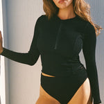 Black long sleeve swim top worn with bikini bottoms, front view showing cropped length