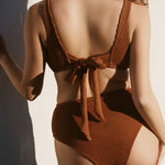 Back shot of wearing brown rust caramel D+ bikini top and high waisted bikini bottom in textured fabric with tie back. 