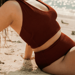Woman wearing a brown halter neck swimsuit on a beach